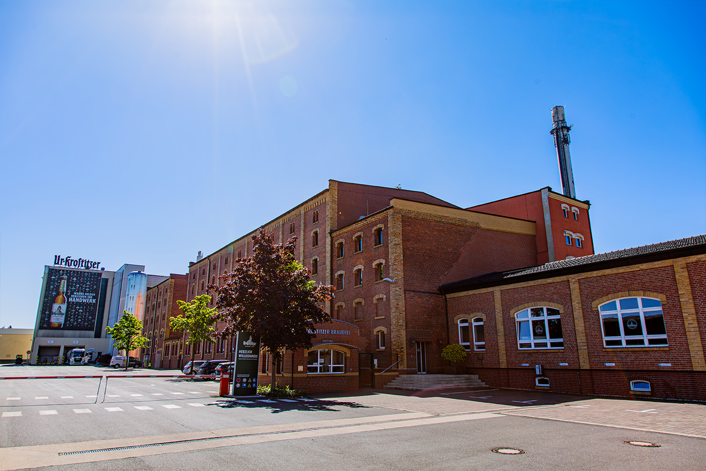 Außenansicht einer Brauerei aus rotem Backstein mit großen Fenstern und einem Schornstein an einem sonnigen Tag