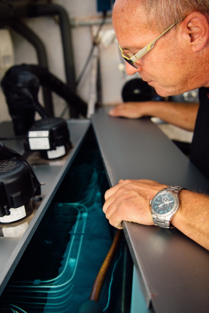 Ein älterer Mann betrachtet eine geöffnete technische Vorrichtung sorgfältig.