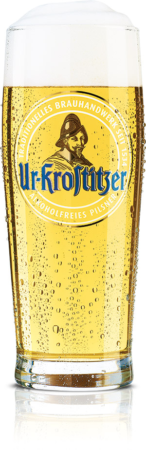 Ein volles Bierglas mit klarem, goldenem Getränk und Blasen steht auf einer weißen Fläche.