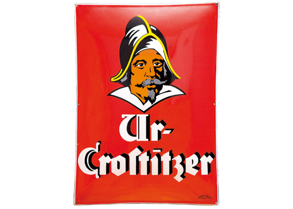 Ein Plakat mit einem charakteristischen männlichen Gesicht in traditioneller Kopfbedeckung auf rotem Hintergrund.