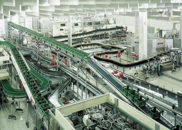 Eine Fabrikhalle mit mehreren Förderbändern, auf denen Flaschen transportiert werden.