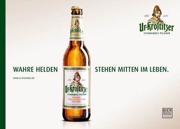 Eine Bierflasche steht auf einem einfarbigen Hintergrund, daneben Slogan und Webadresse.
