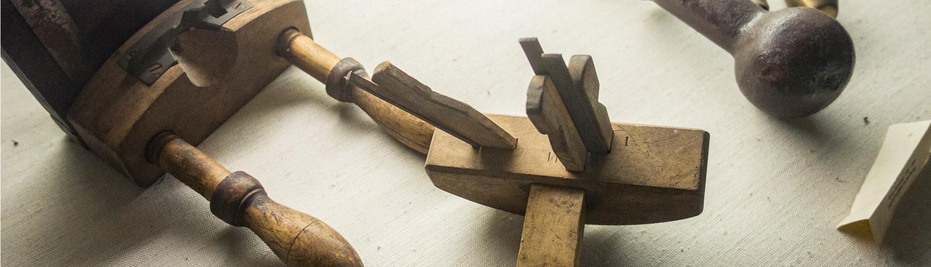 Eine Holzhobelmaschine liegt neben einem Hammer und Meißel auf einem Tisch.