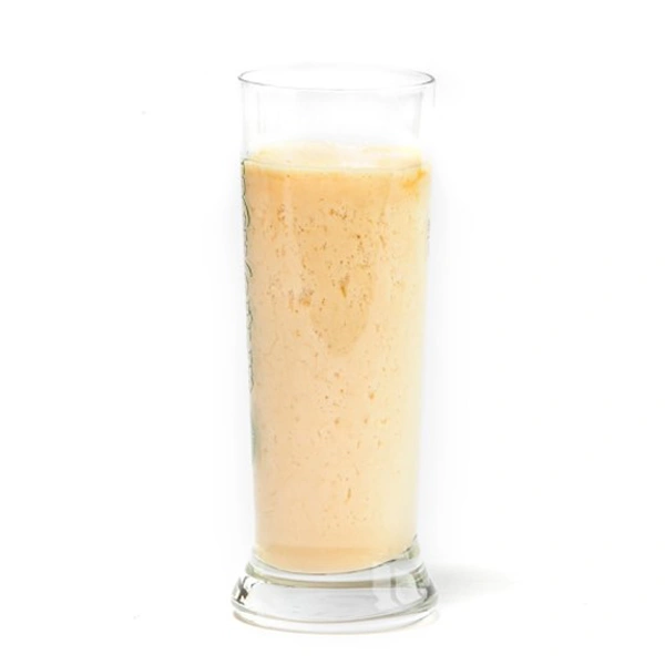 Ein hoher durchsichtiger Glasbehälter ist fast vollständig mit einem gelblichen Getränk gefüllt.