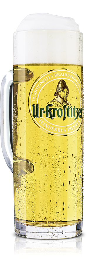 Ein voller Bierkrug steht auf einer reflektierenden Oberfläche. Der Krug ist beschlagen und enthält ein helles Bier.