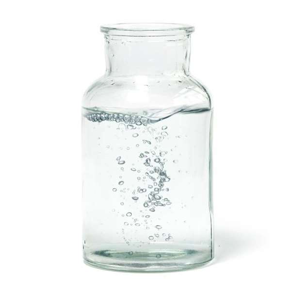 Eine durchsichtige Glasflasche ist teilweise mit Wasser gefüllt und Blasen steigen auf.