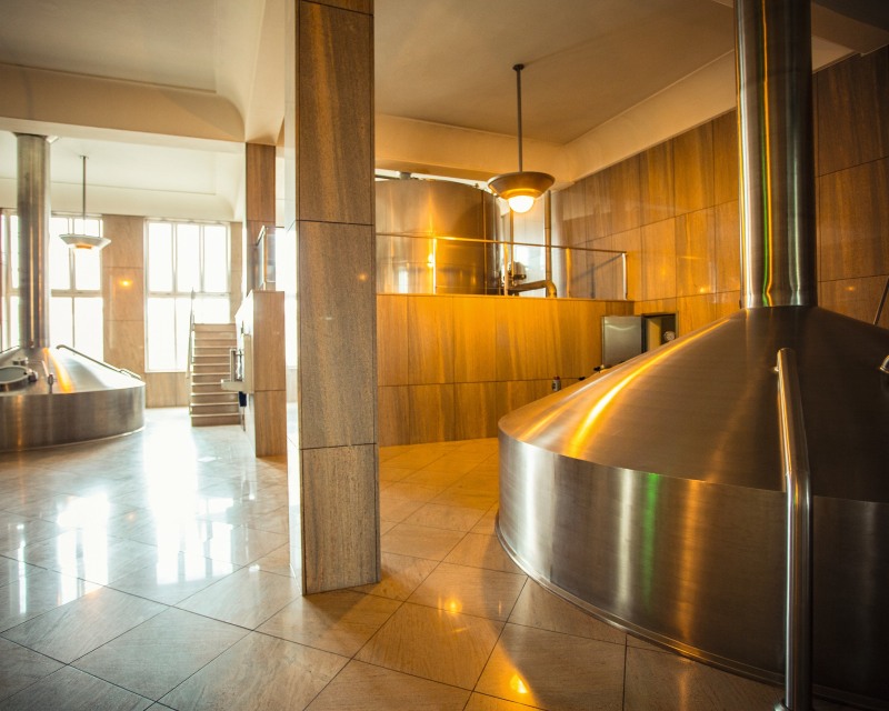 Innenansicht einer Brauerei mit geließtem Boden und Wänden und Sudkessel im Vordergrund