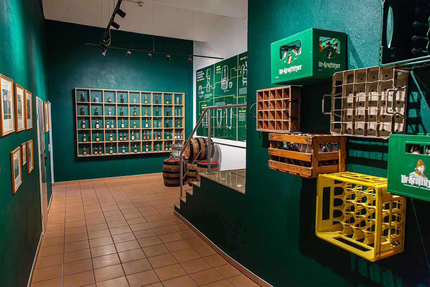Innenansicht eines Ausstellungsraums mit grünen Wänden, an denen verschiedene Bierkästen hängen