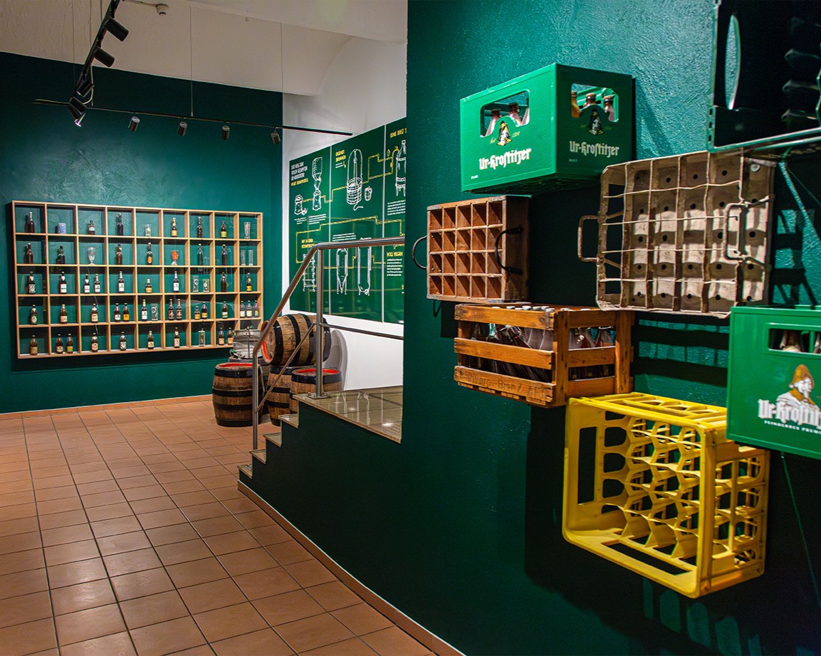 Innenansicht eines Ausstellungsraums mit grünen Wänden, an denen verschiedene Bierkästen hängen