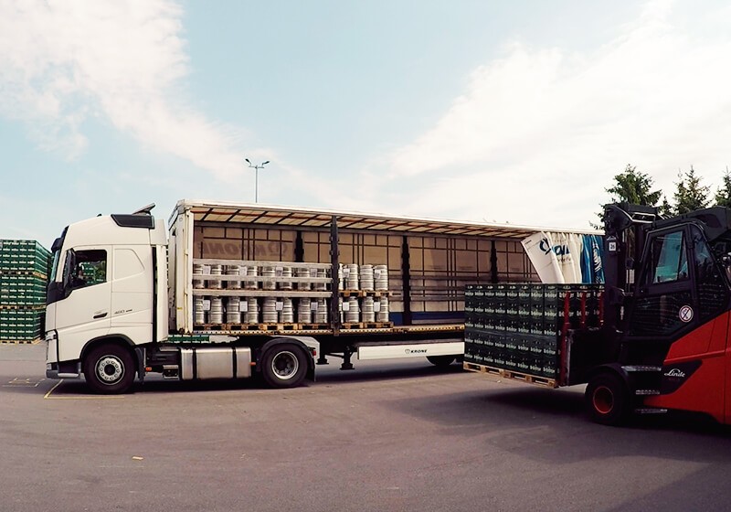 Ein Lkw wird gerade mithilfe eines Gabelstaplers mit Bierfässern beladen.
