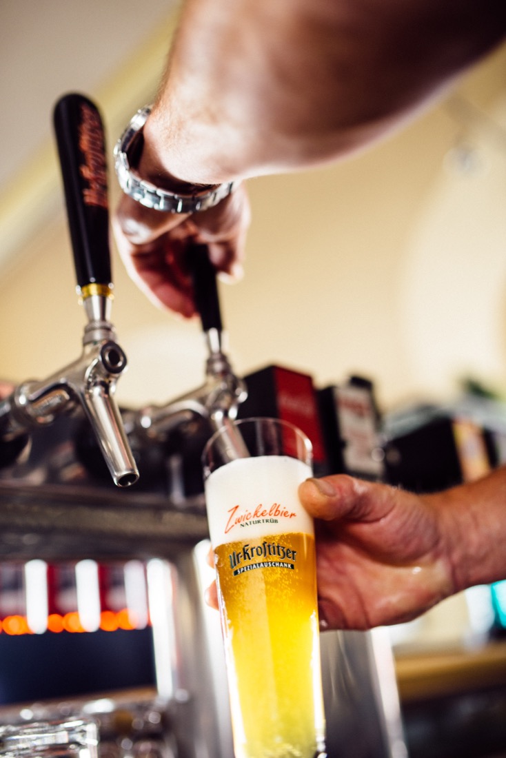 Eine Hand zapft Bier aus einem Hahn in ein Glas.