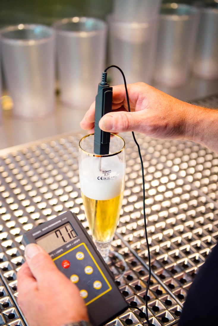 Eine Person misst die Qualität eines Bierglases mit einem digitalen Gerät.