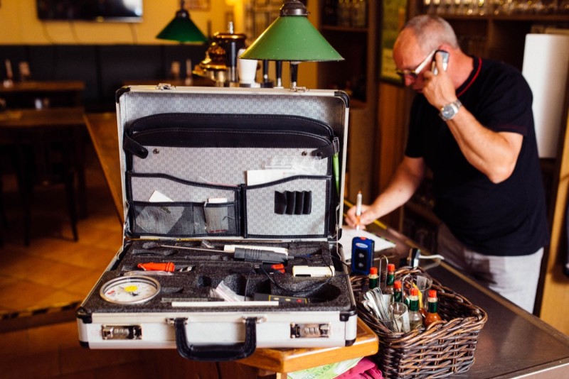 Ein Mann telefoniert und arbeitet an einem offenen Werkzeugkoffer in einer Bar.