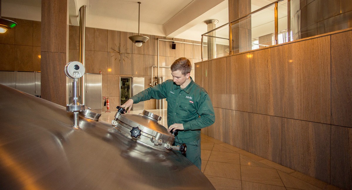 Eine Person in Arbeitskleidung bedient Ausrüstung in einer Brauerei.