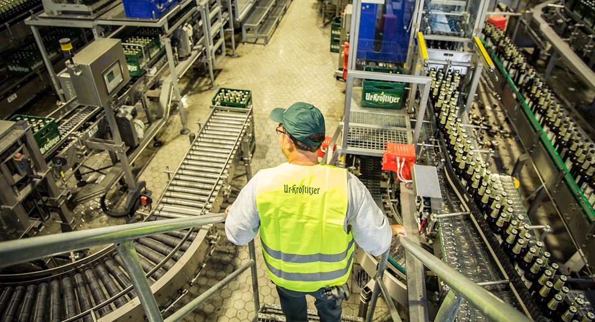 Ein Mann in Sicherheitsweste überwacht eine Abfüllanlage in einer Fabrik.