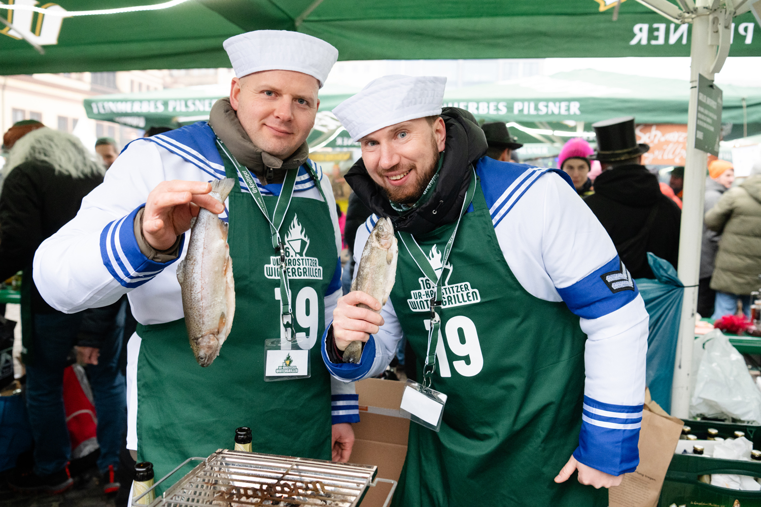 Zwei Männer in Matrosen-Uniform mit jeweils einem Fisch in der Hand