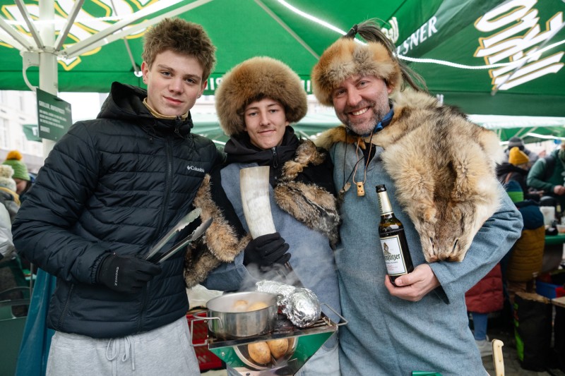 Drei Personen, teilweise in Pelz gekleidet unter einem grünen Sonnenschrim