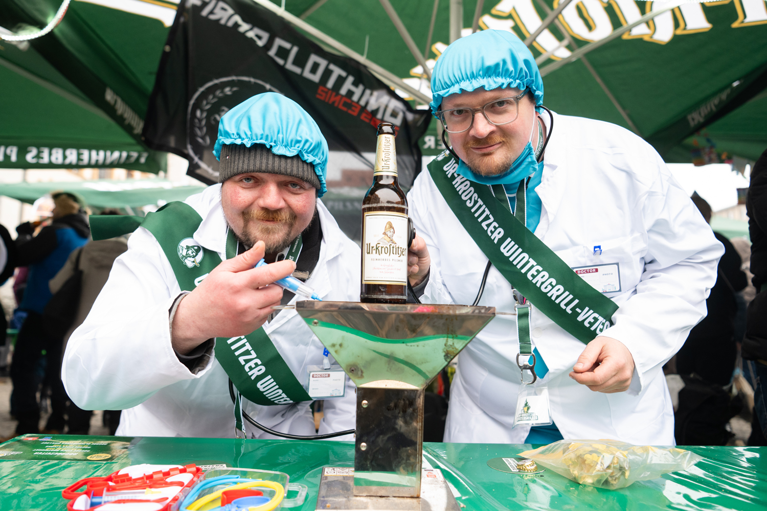 Zwei Personen mit weißem Kittel präsentieren eine Bierflasche