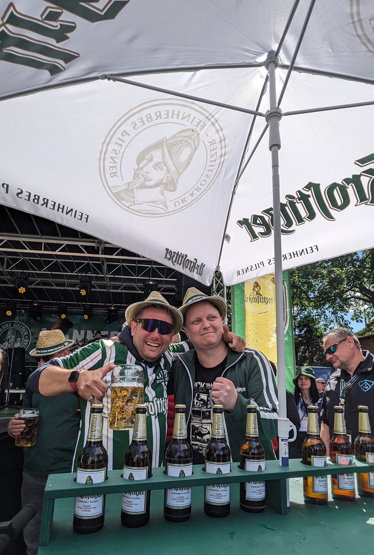 Zwei Männer unter einem Ur Krostitzer Schirm trinken Bier und genießen die Zeit.