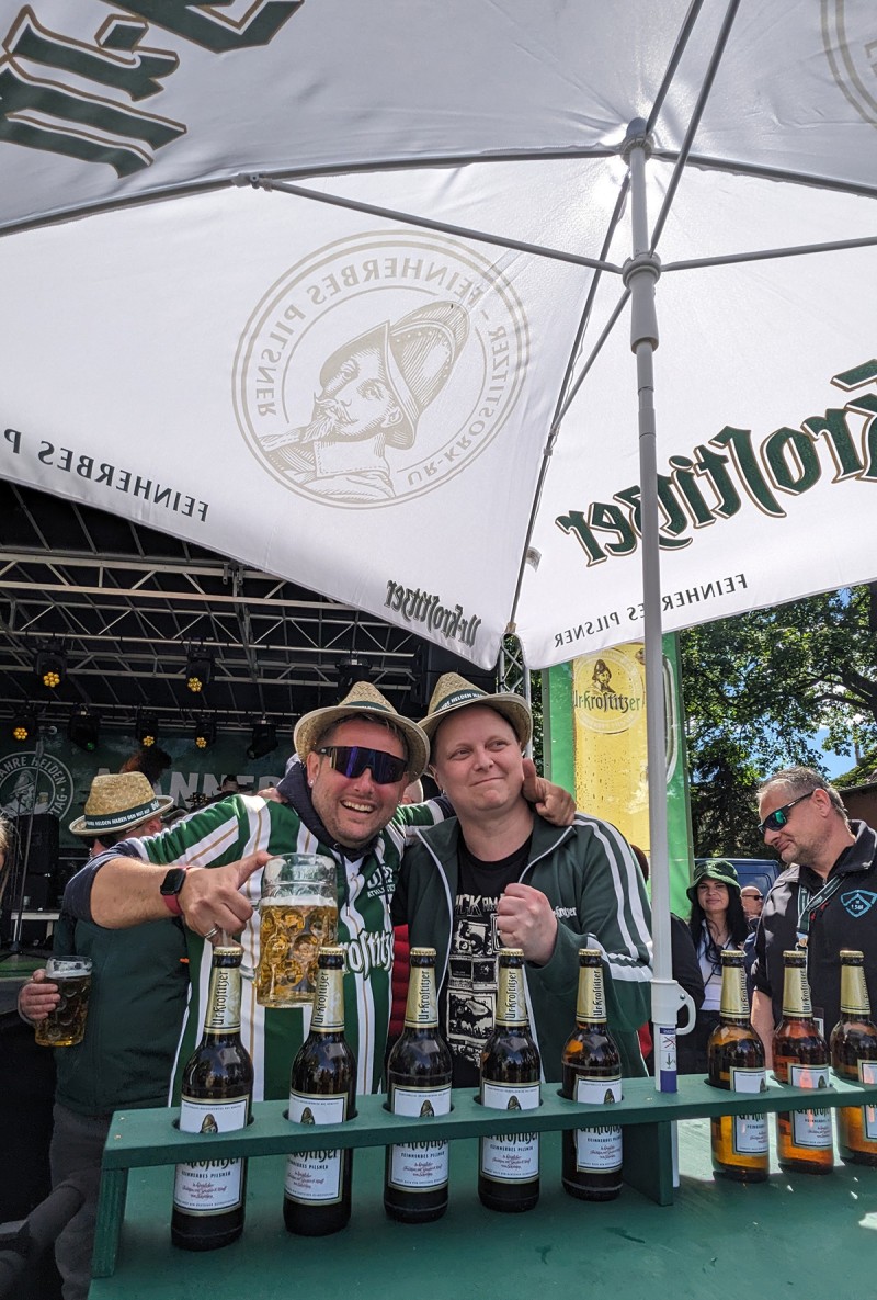 Zwei Männer unter einem Ur Krostitzer Schirm trinken Bier und genießen die Zeit.