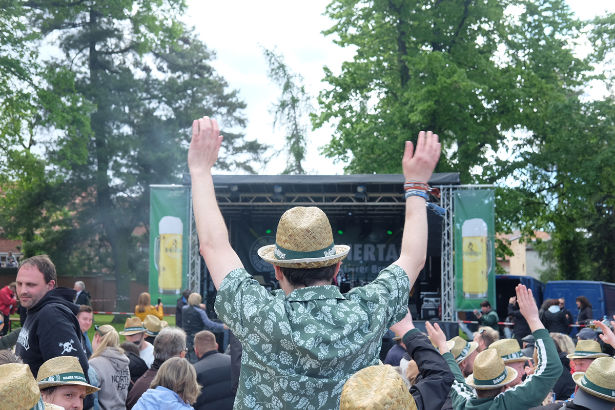 Fans stehen vor der Ur Krostitzer Bühne und Jubeln der Band zu, neben der Bühne stehen Bäume.