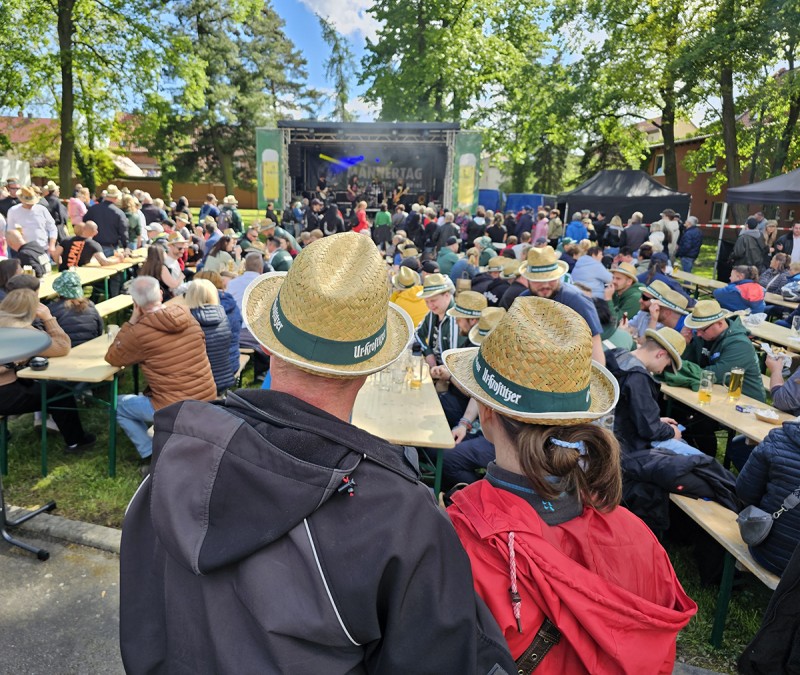Fans stehen und sitzen vor der Ur Krostitzer Bühne und Jubeln der Band zu, neben der Bühne stehen Bäume.