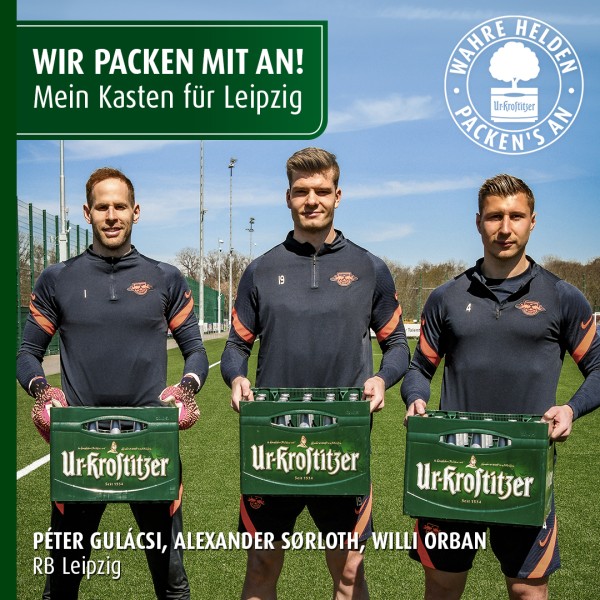 Drei Fußballspieler halten grüne Getränkekästen auf einem Fußballfeld.