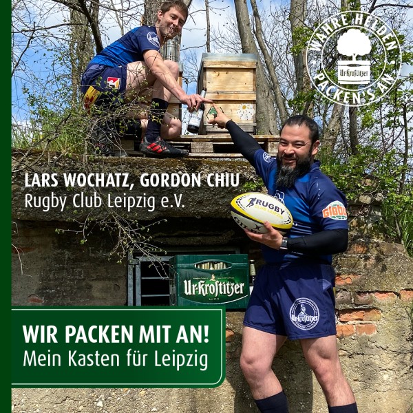 Zwei Männer in Sportkleidung sind bei einer Aktion im Freien aktiv, einer baut oben, der andere posiert mit einem Ball.