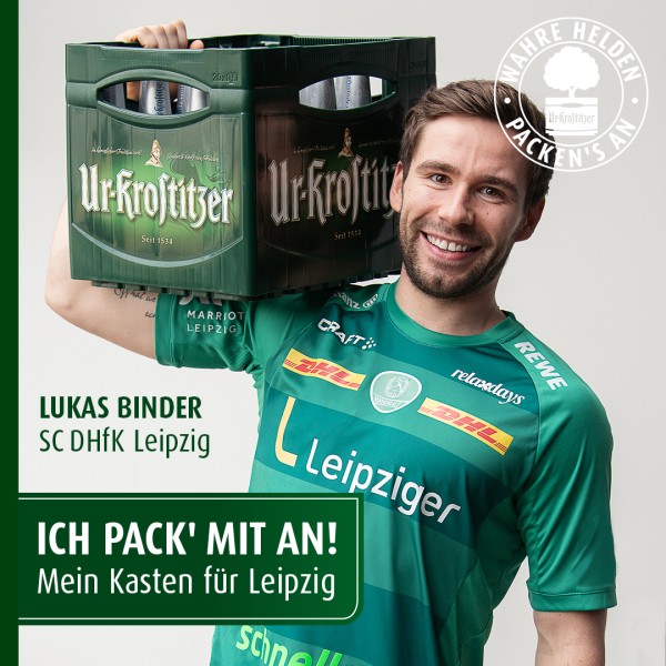 Ein lächelnder Mann in grünem Sporttrikot trägt einen Bierkasten auf der Schulter.