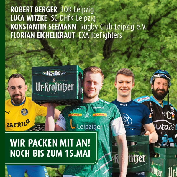 Vier Sportler in Trikots halten gemeinsam einen Getränkekasten in einem Park.