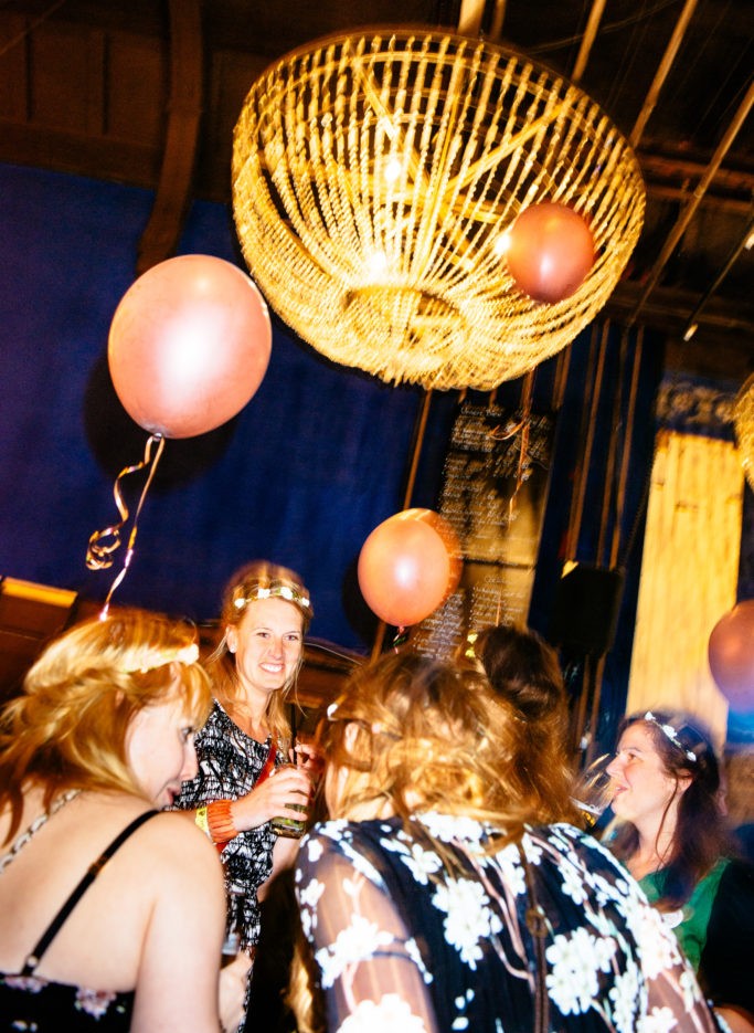 Mehrere Frauen unterhalten sich lächelnd auf einer Party mit Luftballons und einer großen Lampe.