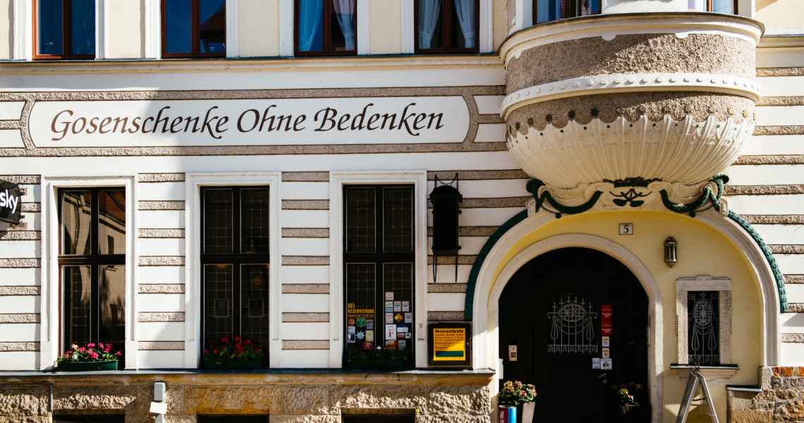 Historisches Gebäude mit gewölbtem Eingang und Fenstern mit Blumenkästen.