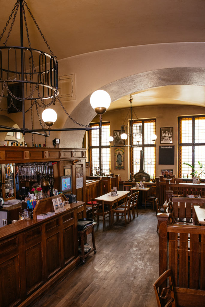Innenansicht eines gemütlichen Cafés mit Holzmöbeln und Bogendecke.