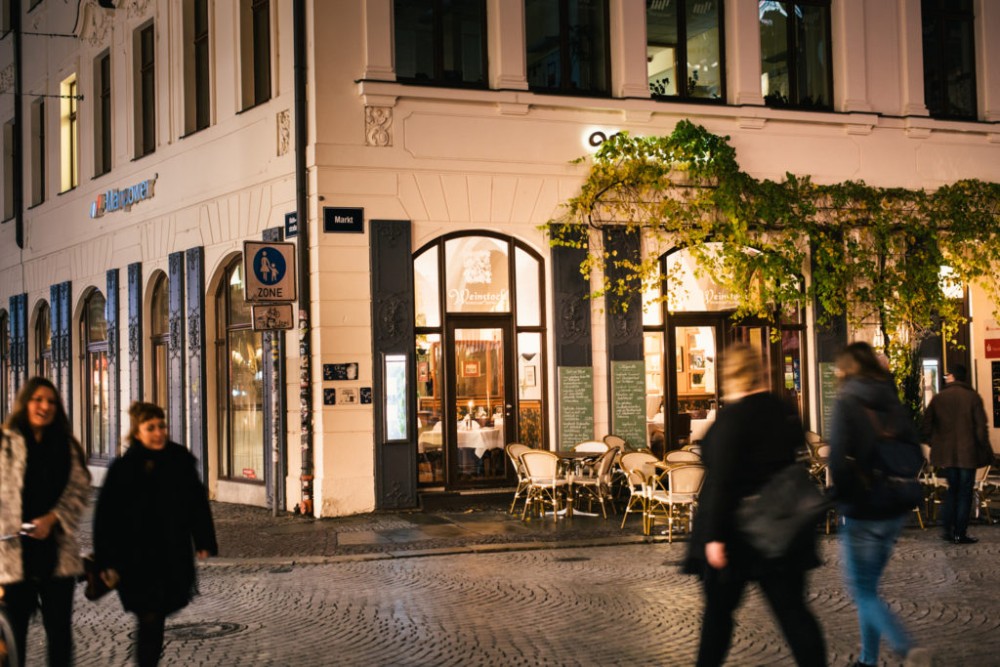 Abendansicht einer belebten Straße mit Restaurantfronten und Passanten.