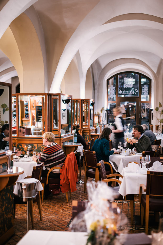 Menschen speisen in einem stimmungsvollen Restaurant mit Gewölbedecken.