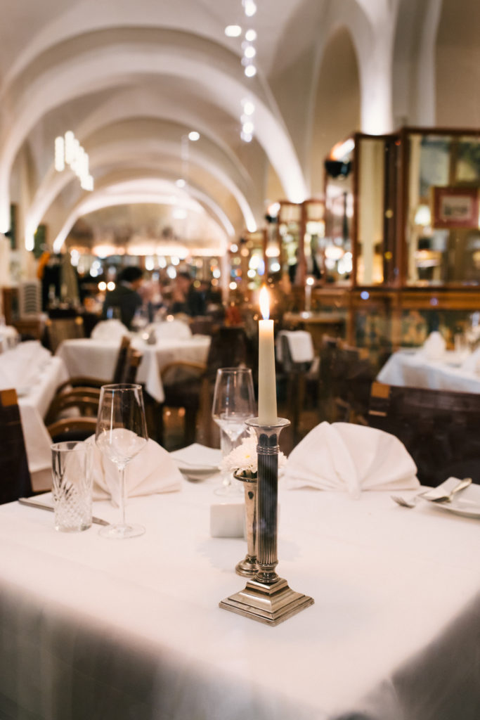 Ein elegantes Restaurant mit gewölbten Decken und Kerzenlicht auf den Tischen.