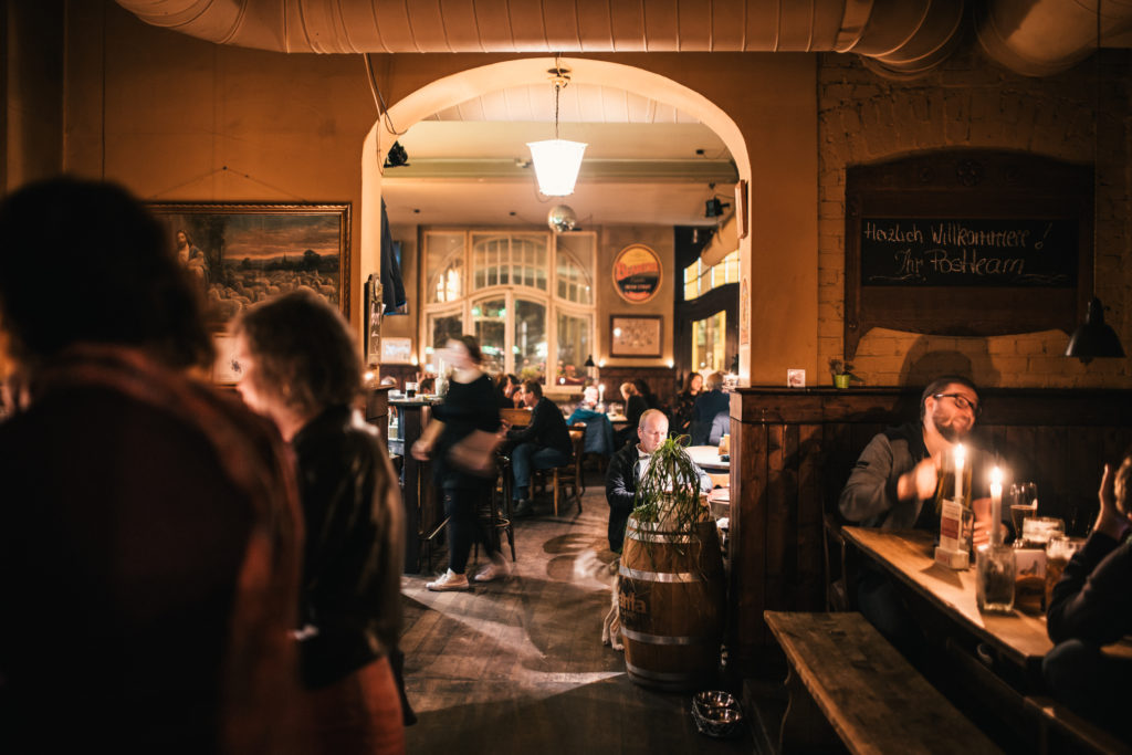 Gemütliche Szenerie in einem belebten Restaurant mit Kerzenlicht und Gästen beim Essen.