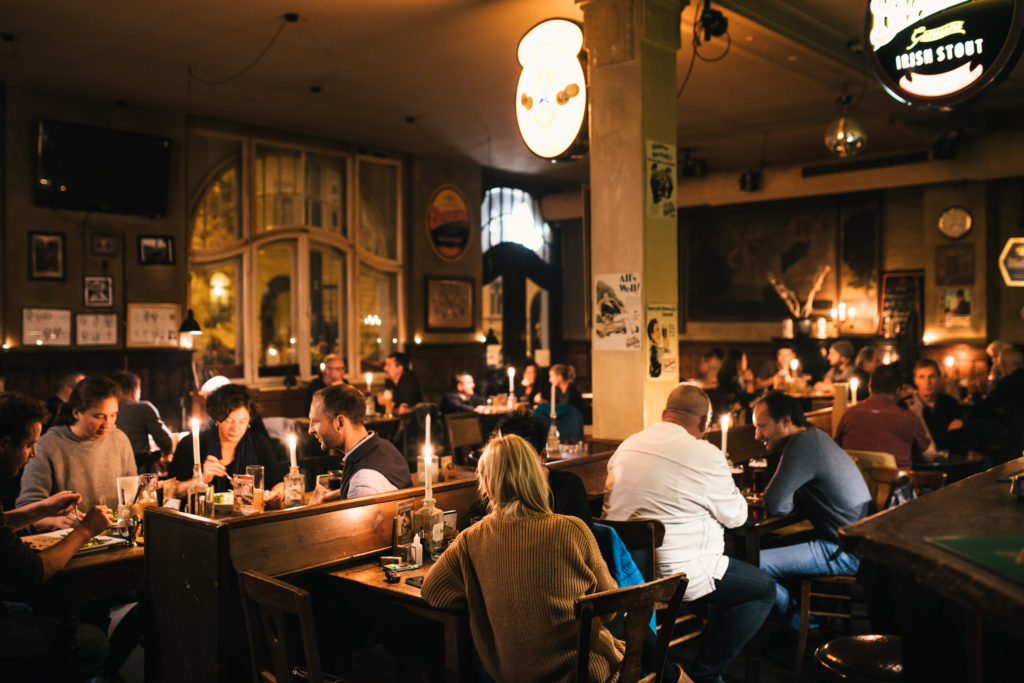 Menschen sitzen in einem belebten Pub und genießen Getränke und Gespräche.
