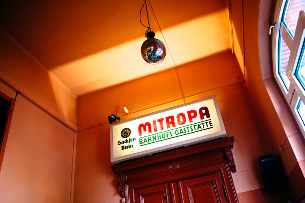 Eine Discokugel hängt an der Decke über einem Schild mit Leuchttext in einem Raum.