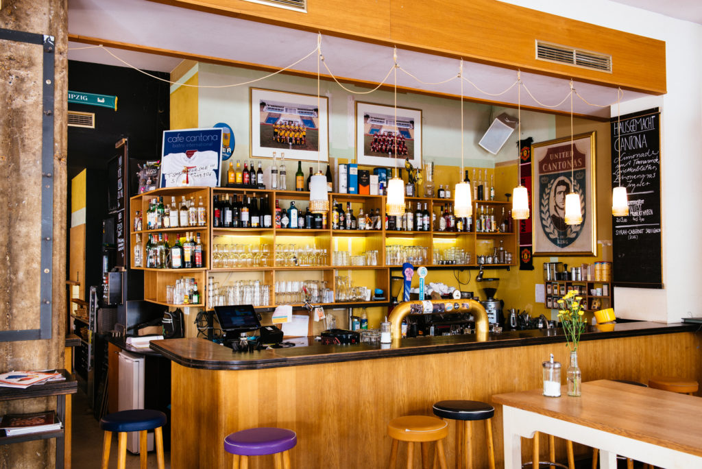 Eine Bar mit vielen Flaschen auf Regalen und einer Kaffeemaschine auf der Theke.