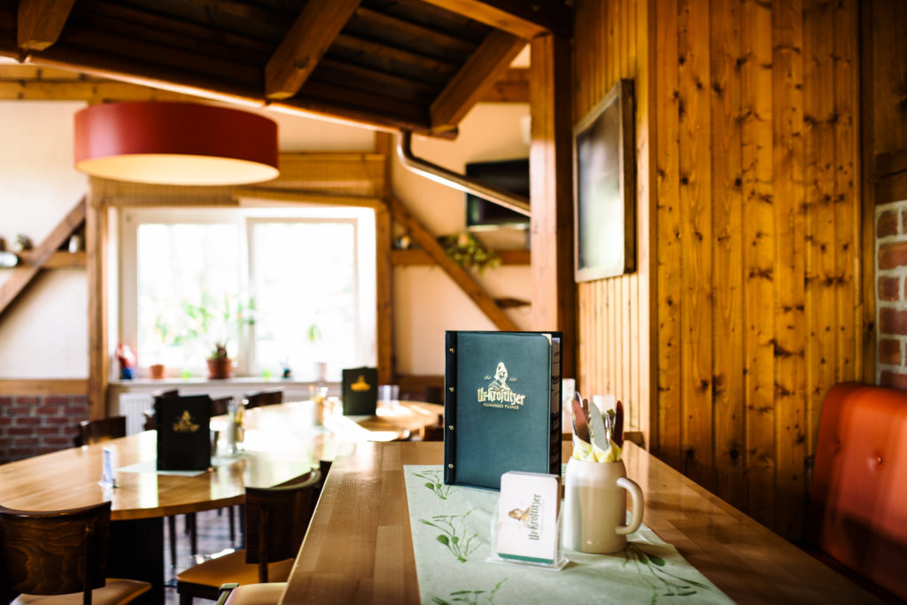 In einem rustikalen Restaurant mit Holzvertäfelung steht ein Speisekartenständer auf einem Tisch.