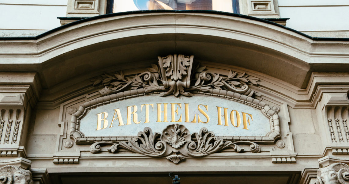 Ein steinernes Bogenportal zeigt eine verzierte Inschrift mit dem Namen eines historischen Gebäudes.