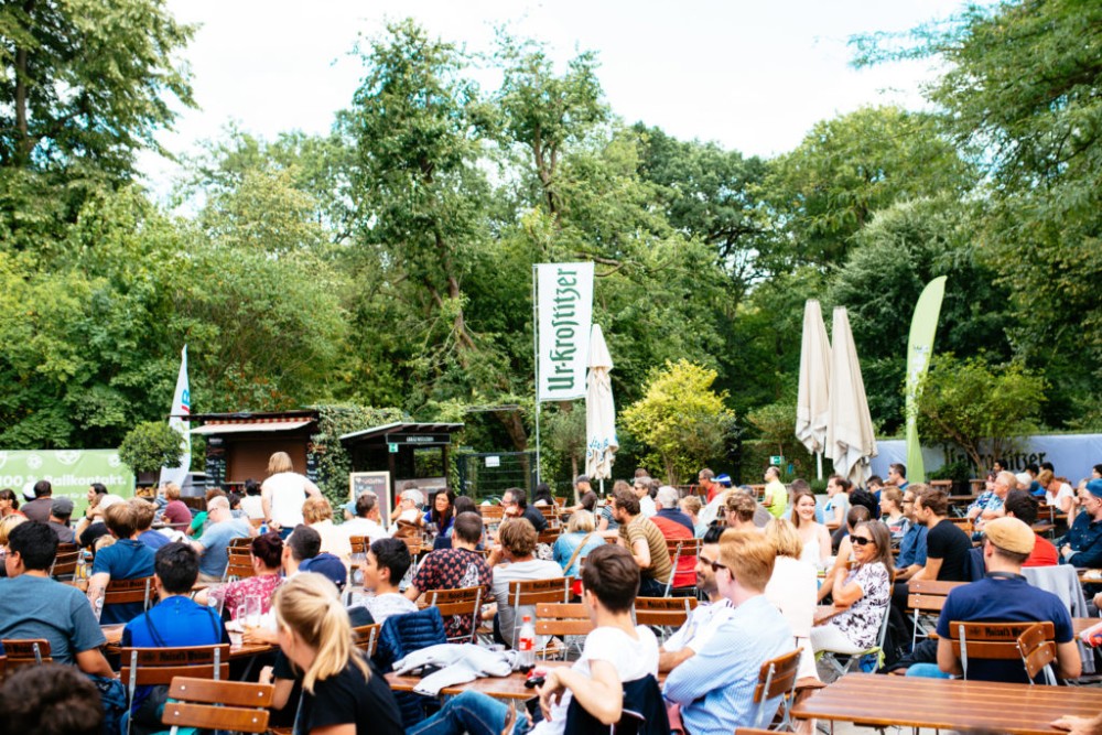 Eine Gruppe Menschen sitzt draußen in einem Park bei einem öffentlichen Event.