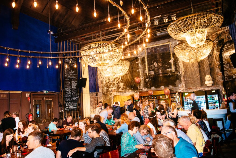 Ein belebtes Restaurant mit Gästen an Tischen und eleganten Kronleuchtern.