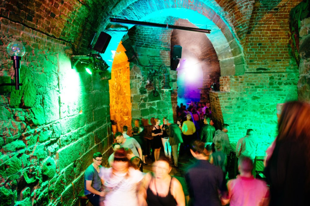 Menschen genießen eine Party in einem beleuchteten Gewölbekeller.