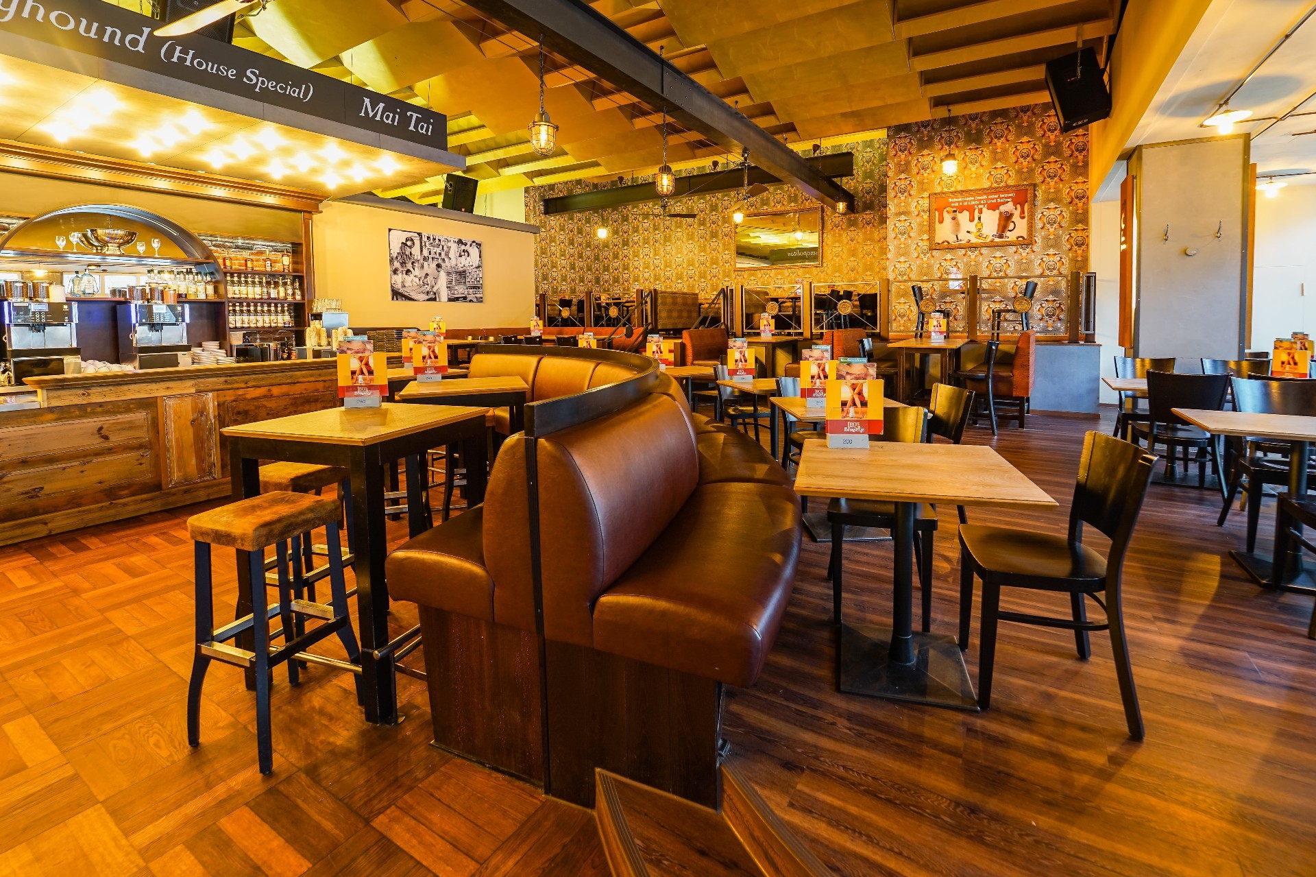 Ein Barkeeper zapft Bier in einer belebten Bar mit vielen Gläsern und Flaschen im Hintergrund.
