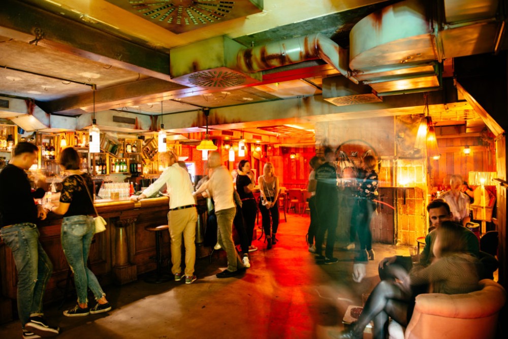 Eine belebte Bar mit Gästen, die Getränke bestellen und sich unterhalten.