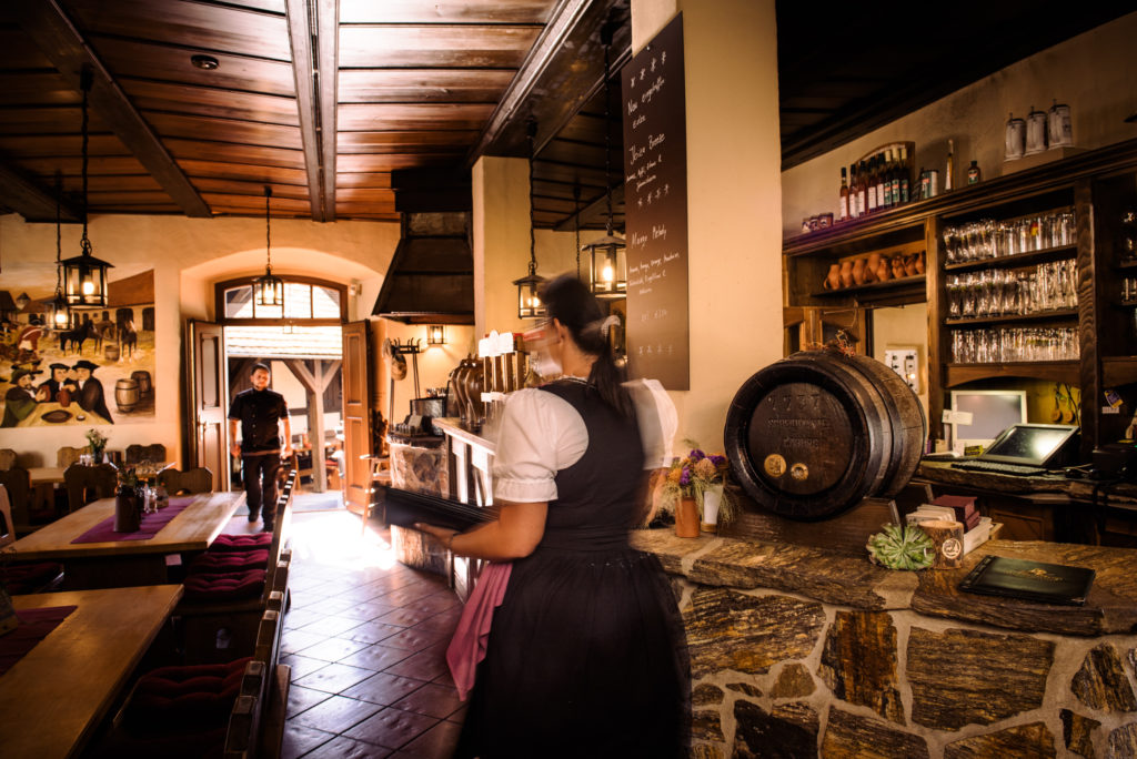 Eine Kellnerin trägt Getränke durch ein rustikal eingerichtetes Restaurant.