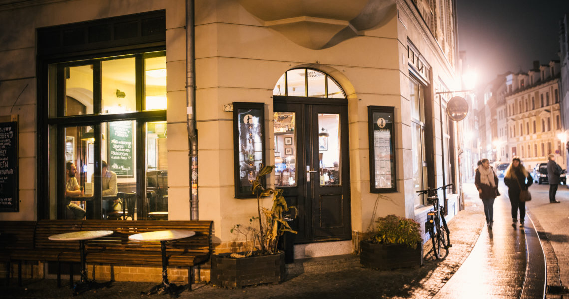 Zwei Personen sitzen abends in einem beleuchteten Café an einem Fenster.