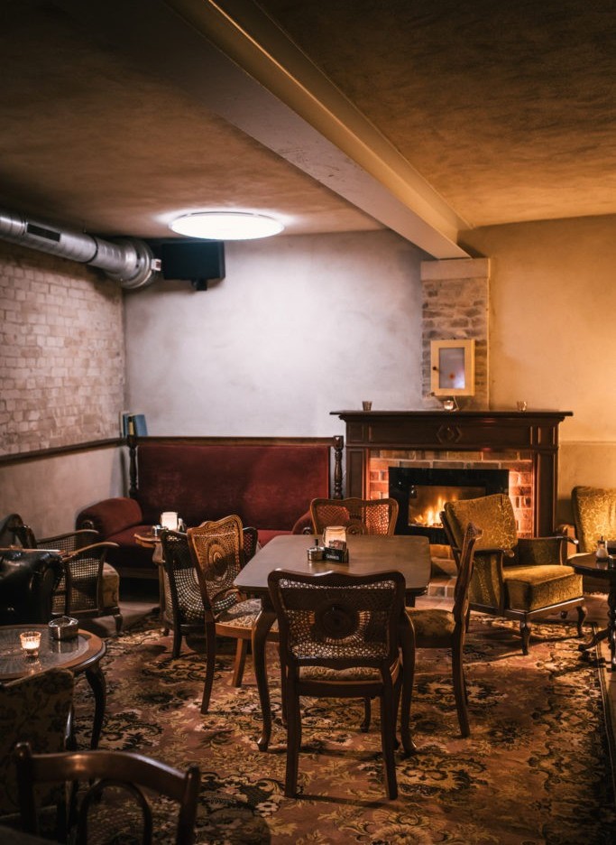 Ein gemütlicher Raum mit Kamin, Holzmöbeln und einer gedämpften Beleuchtung.